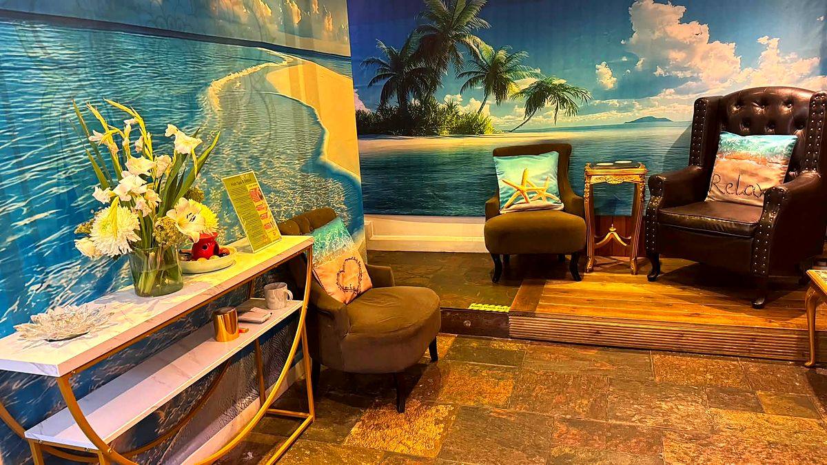 The waiting lounge at Taitam-D, painted wall to wall with a tropical beach, with leather armchairs
