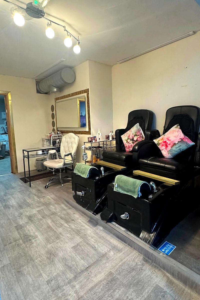 Pedicure spa chairs with cushions and green towels beside a mirrored styling station